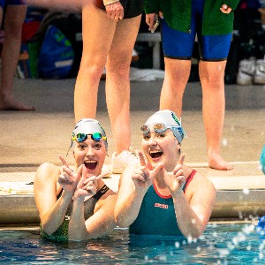 Swimmers make a "W' with their hands to celebrate winning